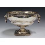 A George V silver circular fruit bowl with egg and dart rim above a pair of lion mask and loose ring