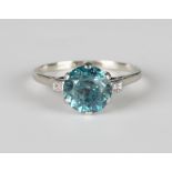 A white gold and platinum ring, claw set with a circular cut blue zircon between two baguette