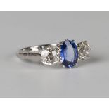 A platinum, sapphire and diamond ring, claw set with an oval cut sapphire between diamond single