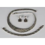 A silver collar necklace in a curved pierced rectangular Greek key style link design graduating in