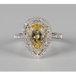 An 18ct white gold, yellow beryl and diamond cluster ring, claw set with a pear shaped yellow