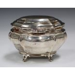 An Edwardian silver tea caddy of oval bombé form with hinged lid, on scroll feet, London 1904 by