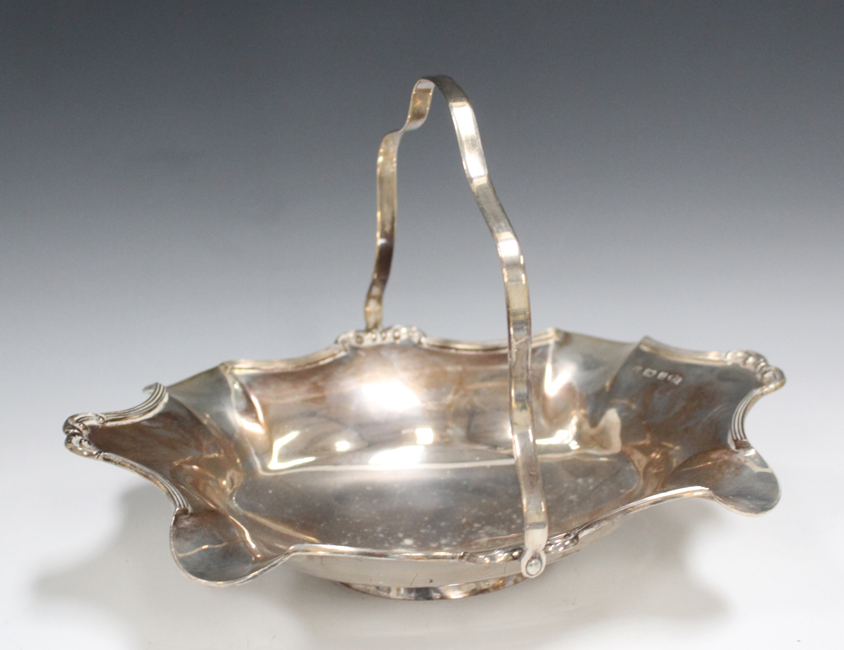 A George V silver swing handle basket with shaped scroll rim, Birmingham 1910 by Mappin & Webb,