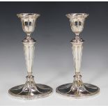 A pair of Edwardian silver candlesticks, each oval urn shaped sconce with beaded rim, above a