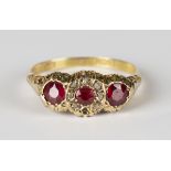 An Edwardian 18ct gold ring, mounted with three circular cut red gems, the central red gem mounted