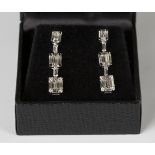 A pair of white gold and diamond pendant earrings in a graduated design, mounted with baguette and