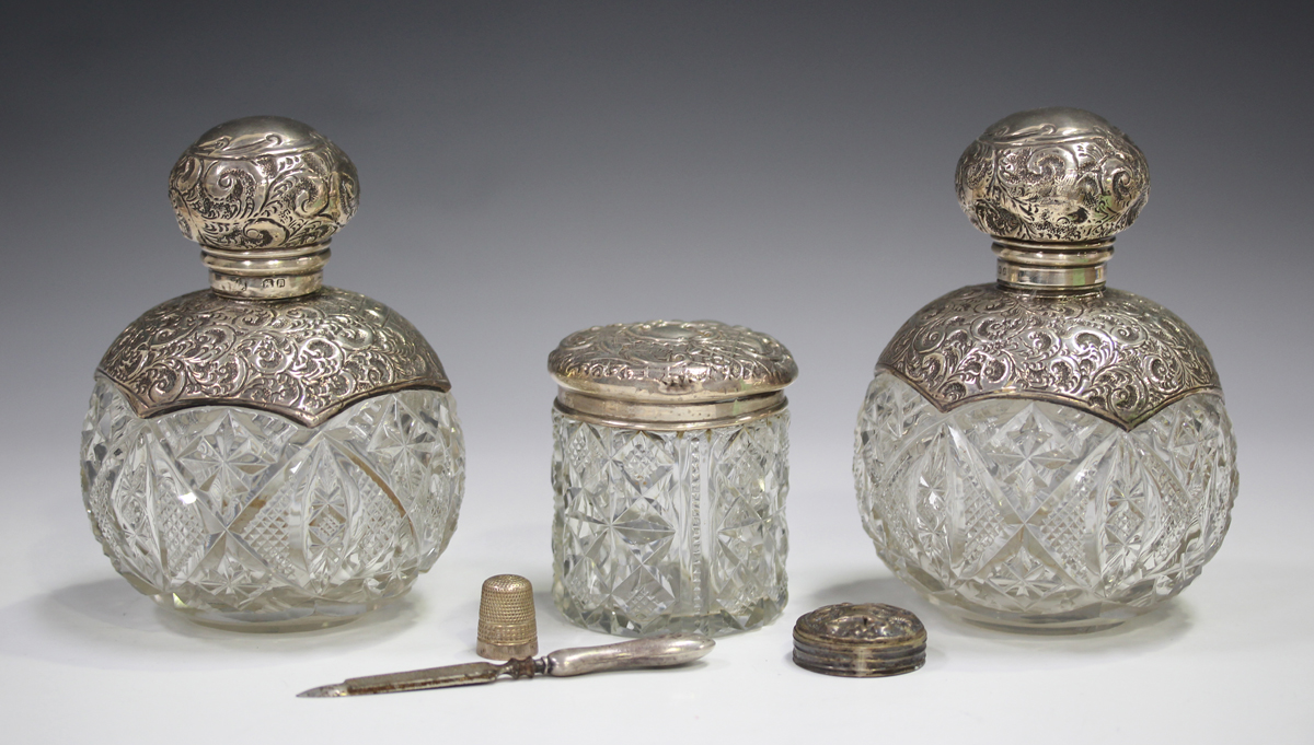 A pair of Edwardian silver mounted cut glass perfume bottles, the collars and screw tops embossed