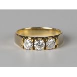 A gold and diamond three stone ring, claw set with circular cut diamonds, detailed '750', ring