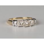 A gold and diamond three stone ring, mounted with a row of princess cut diamonds, the principal