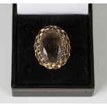 A 9ct gold ring, claw set with an oval cut smoky quartz within a pierced surround, ring size