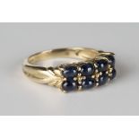A 9ct gold ring, mounted with two rows of four oval cabochon sapphires, detailed '9K', ring size