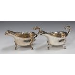 A pair of George V silver sauce boats, each with shaped rim and foliate capped scroll handle, on