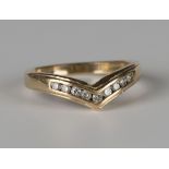 A 9ct gold and diamond set wishbone shaped ring, mounted with a row of nine circular cut diamonds,