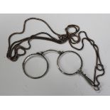 A pair of plated folding lorgnettes, fitted with circular lenses, with a Brazil link neckchain