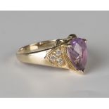 A 9ct gold ring, mounted with a pear shaped amethyst between circular cut diamond set three stone