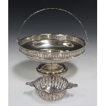 A George V silver circular fruit basket with pierced rim and overhead swing handle, on a circular