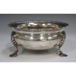 An Edwardian silver circular sugar bowl with scalloped rim, raised on stylized shell feet, London