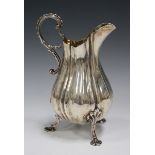 An early Victorian silver milk jug of lobed baluster form with scroll handle, on scallop shell