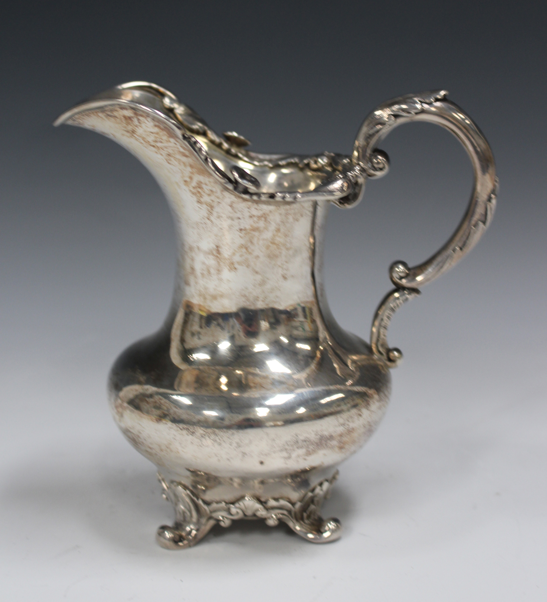 A William IV silver milk jug with floral and foliate cast rim, foliate capped scroll handle, and