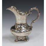 A William IV silver milk jug with floral and foliate cast rim, foliate capped scroll handle, and