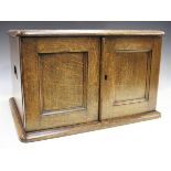 An Edwardian oak canteen box with a pair of panelled doors revealing four graduated drawers with