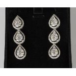 A pair of white gold and diamond triple cluster pendant earrings, each cluster in an open drop