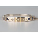 A gold, diamond and sapphire oval hinged bangle, the front mounted with three circular cut