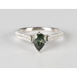 A white gold, green sapphire and diamond ring, claw set with a pear shaped green sapphire between