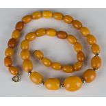 A single row necklace of graduated oval vari-coloured opaque butterscotch coloured amber beads on