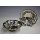 A pair of George V silver circular bonbon dishes, each with pierced foliate panels and cast scroll