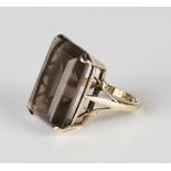 A 9ct gold ring, claw set with a rectangular step cut smoky quartz between split shoulders, detailed