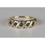 A gold, sapphire and diamond ring, mounted with a row of five circular cut sapphires with pairs of