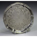 A Victorian silver card salver with beaded shaped rim and engraved foliate band, raised on three