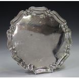 A George V silver salver with shaped piecrust rim, on four volute scroll feet, Sheffield 1913 by