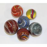 A group of six glass marbles, each with coloured swirls, diameters 2cm to 2.5cm.Buyer’s Premium 29.