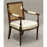 A late George III mahogany showframe bergère library armchair, the caned panel back above stop