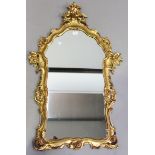 A late 20th century giltwood wall mirror with a carved floral frame, 110cm x 67cm (chip to frame).