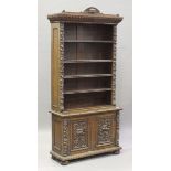 A late Victorian carved oak open bookcase, decorated with overall masks and scrolls, the four