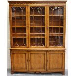 A 20th century reproduction yew bookcase cabinet with blind fretwork borders, height 202cm, width