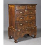 A George I walnut and elm chest-on-stand, the eight crossbanded drawers with original brass