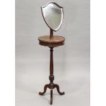 An Edwardian mahogany shaving stand with shield shaped mirror, on a turned column and tripod feet,