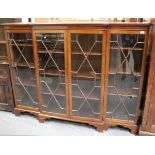 An Edwardian mahogany breakfront bookcase, the four astragal glazed doors enclosing adjustable