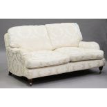 A modern Howard style sofa, upholstered in patterned cream damask, on turned legs and castors,