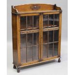 A George V oak bookcase, the gallery back above a pair of glazed doors enclosing two shelves, on