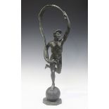 An early 20th century verdigris patinated bronze figure of a male nude standing on a sphere,