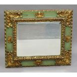 An early 20th century Continental green painted and gilded carved softwood wall mirror with a