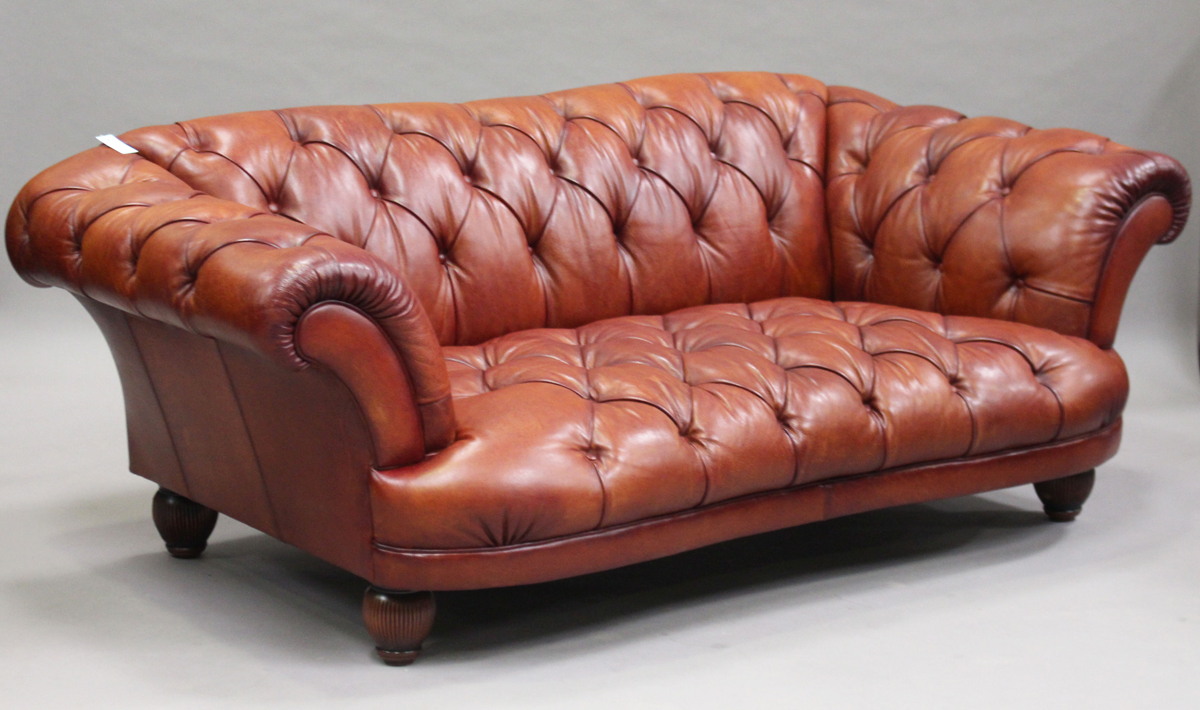 A modern Chesterfield style buttoned brown leather settee, raised on reeded hardwood legs, height