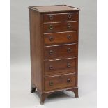 An Edwardian mahogany narrow chest, carved with a flower and ribbon-swagged band, on bracket feet,