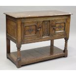 A 20th century Jacobean Revival oak side cabinet with carved decoration, enclosed by two doors, on