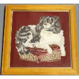 A 20th century woolwork panel of a King Charles spaniel recumbent upon a pillow, 39cm x 39cm, within